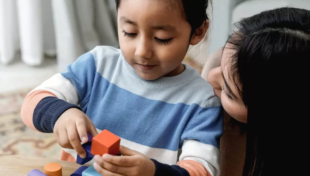 A woman helping a girl with a block puzzle