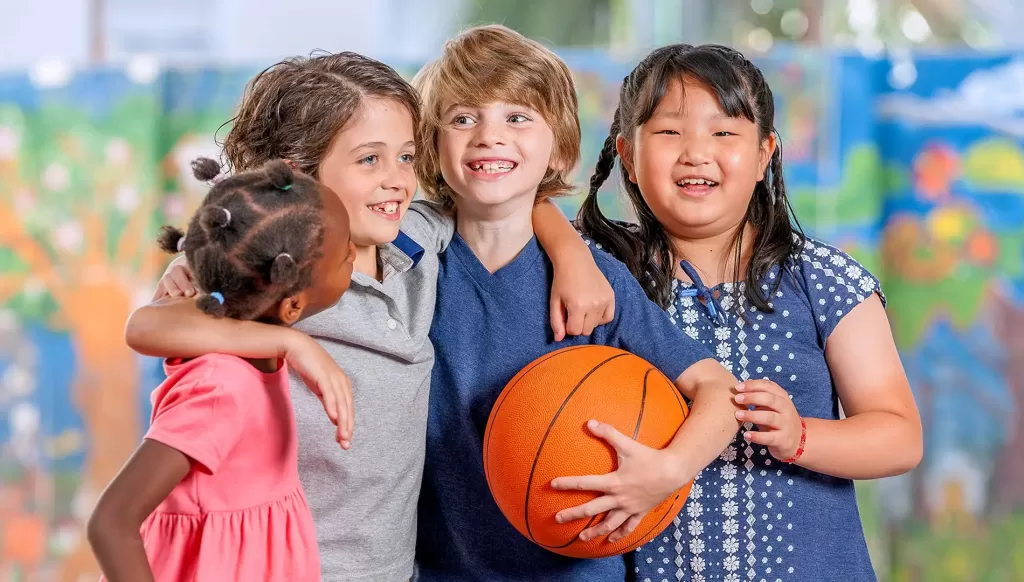A group of 4 children smiling with a basketball