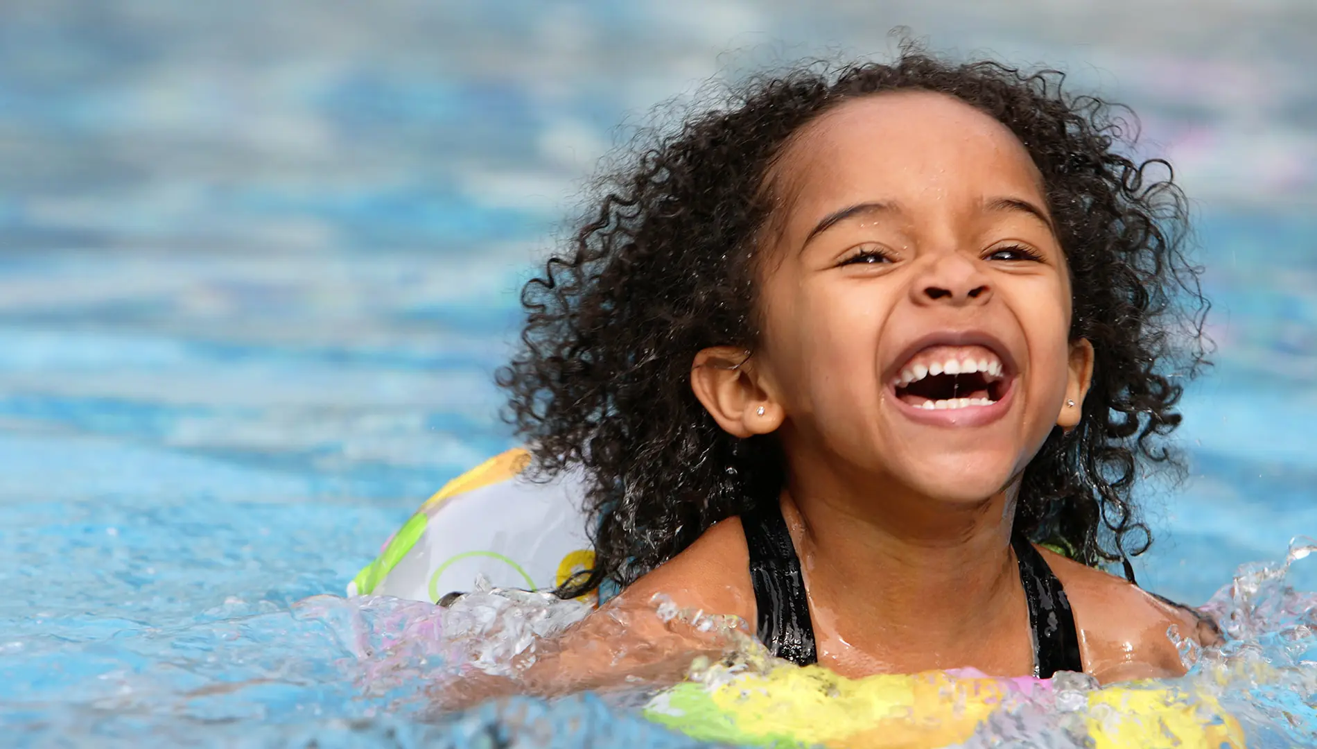 Child smiling as she swims in a pool